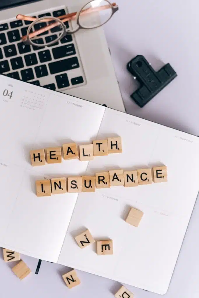 Words Health Insurance Made of Wooden Letter Tiles and Lying on a Calendar and Laptop